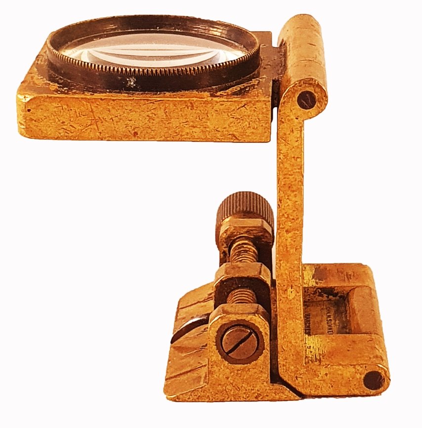 A gold metal device with a magnifying glassDescription automatically ...